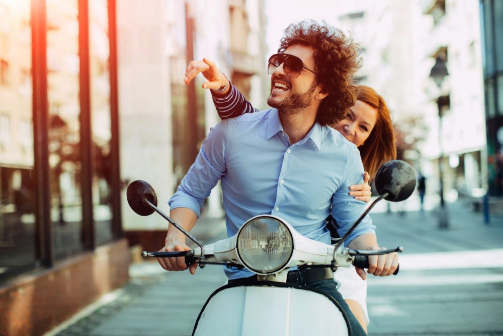 [516895448] Cheerful Young Couple Riding On A Motorbike.